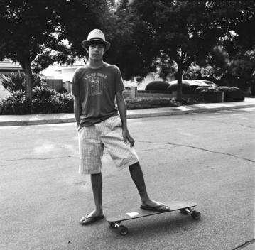 Boy With Skateboard On Surburban Street