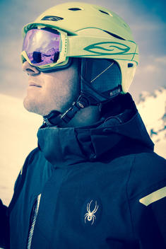 Close-up of a guy wearing a SPYDER skiing outfit, he is posing in a snowy mountainous landscape
