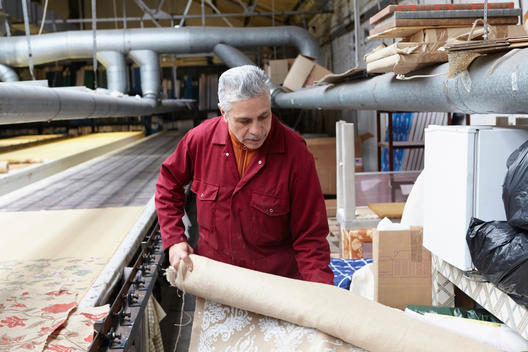 Man holding roll of fabric in textiles factory