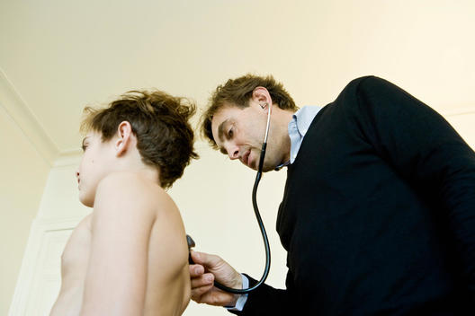 Doctor examining young patient, using stethoscope