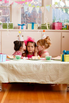 young girls telling secrets at indoors birthday party