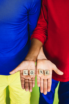 close up of hands of two children holding scrabble pieces forming the word LOVE