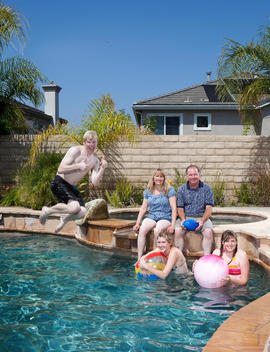 A family enjoys the pool in the backyard of their home