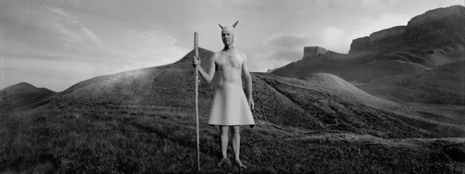 Horned Man With A Staff In A Barren And Hilly Landscape