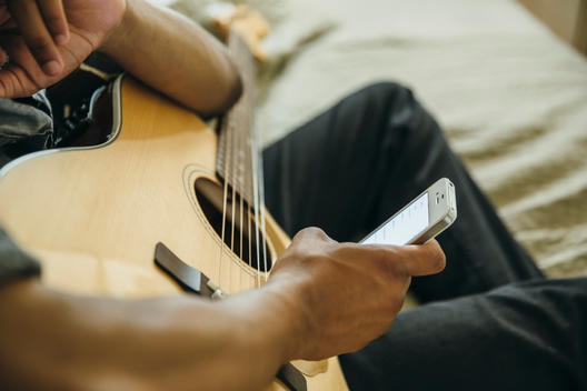 Mixed race boy with guitar using cell phone
