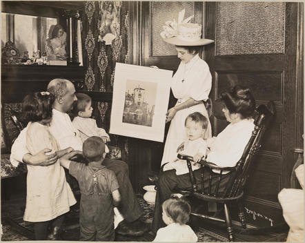 A Woman Showing A Poster To A Man, Woman, And Children.
