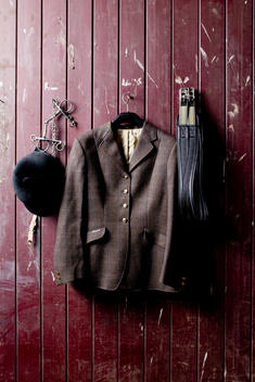 Still life of horse riders clothes hanging on stable wall