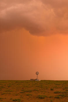 Intense desert thunderstorm at sunset with windmill