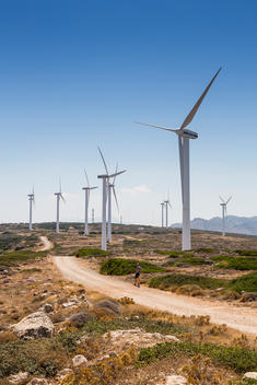 Wind Turbines with father and son on the cliff top outside of Elounda looking out on to the Aegean Sea, Crete, Greece.