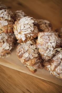 A group of fresh baked almond croissants, with icing sugar dusting. Organic party food desserts.