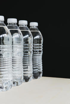 Row of clear, plastic water bottles filled with filtered water in a row. on a black background.