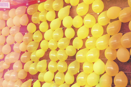 Wall of bright yellow balloons on a boardwalk game