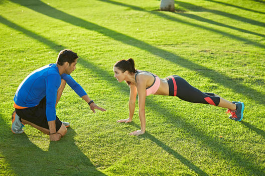 Personal trainer with woman doing plank exercise