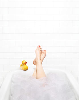 Feet up in bubble bath with rubber duck
