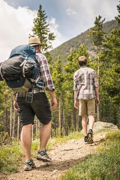 Full length rear view of father and son trekking through forest to mountain, Red Lodge, Montana, USA