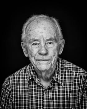 Black and white portrait of elderly man wearing a plaid shirt no smile
