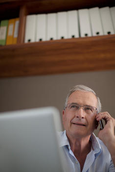 Older man talking on cell phone at desk