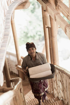 Balinese man carrying rolled towels in hotel, Ubud, Bali, Indonesia