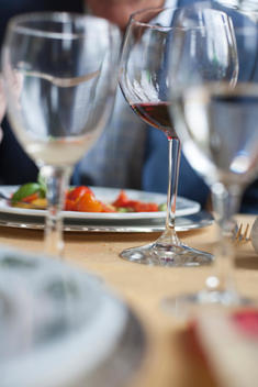 Close up of wine glasses and plate on table with man in background out of focus