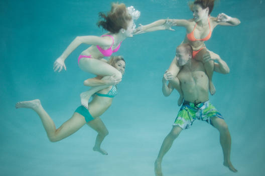 4 people playing chicken fight underwater