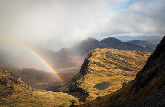 Passing storm, rainbow and mountain lake, Red Cuillin from Bla Bheinn mountain, Isle of Skye, Scotland