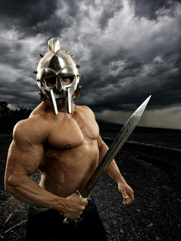 bodybuilder in helmet with sword and stormy background