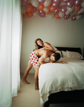 Smiling couple wrestling on bed
