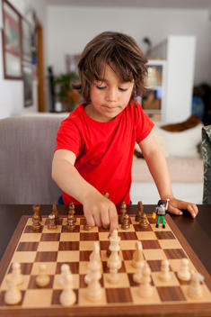 Little boy playing chess at home