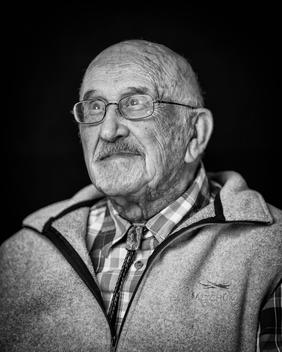 Black and white portrait of elderly man wearing glasses with fleece vest looking away