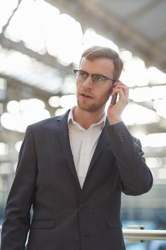 Mid adult businessman using smartphone to make telephone call, looking away