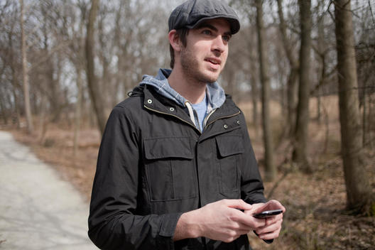 Hip Young Man Checks His Phone In A Forest Preserve In The Suburbs Of Chicago.