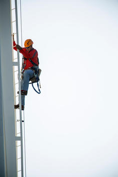 Caucasian worker climbing tower on site