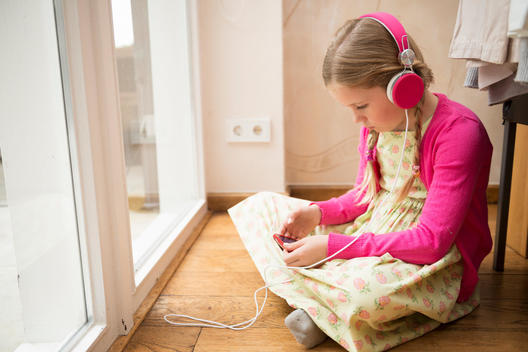 Girl sitting on floor selecting music for headphones