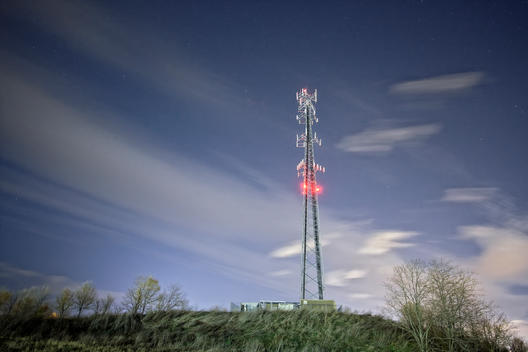 Cell tower at night on a green hill