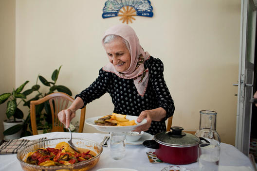 Elderly Turkish woman is serving traditional Turkish food for her guests at her home.