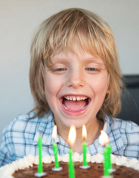 Austria, Boy laughing and looking at birthday cake, close up