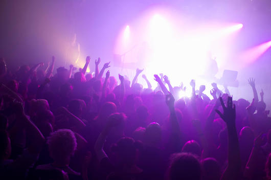 Rays of purple spotlights over crowded dance floor at nightclub