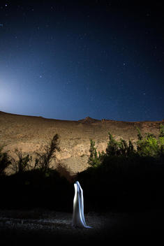 Starry sky at night with mountain and veiled figure standing alone