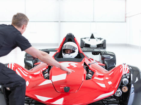 Engineer and racing car driver in supercar in sports car factory