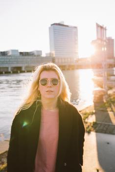 Portrait of a young, caucasian woman in the docklands of Amsterdam. Photo taken during dusk or sunset in Amsterdam.