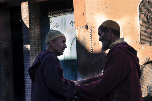 Two men greet one another on a street in Marrakech.