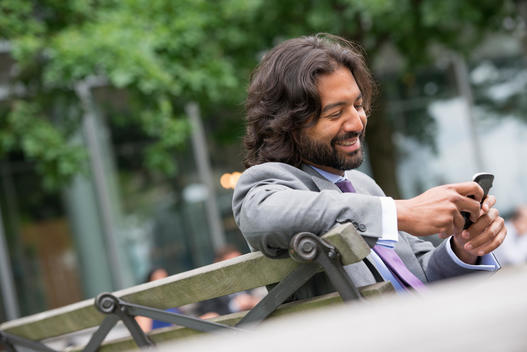 Business People. A Man In A Business Suit With A Full Beard And Curly Hair. Using His Phone.