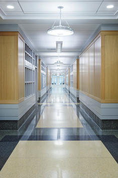 Commercial interior hallway with woods walls, granite floors and glass doors at the end.