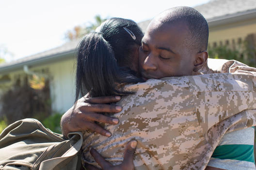 Close up of female soldier hugging husband on homecoming
