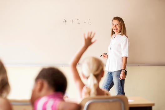 Mature teacher teaching mathematics to children in classroom