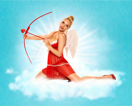 Blonde pin-up girl dressed as a sexy Cupid in red lingerie with wings, Paris, France.