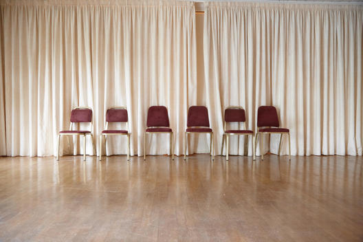 A line of chairs in front of beige curtains.