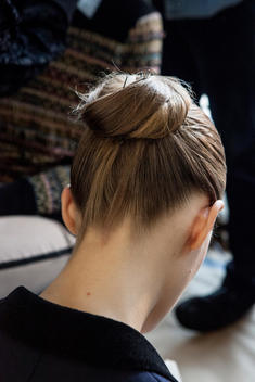 A model\'s head with her hair in a tight bun with pins, as she is being primped for NY Fashion Week.