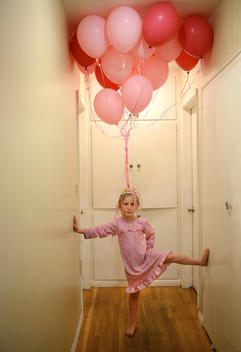 Little girl, age 5-7, has fun at a birthday party wit creative balloon play