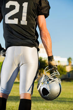 Rear view of football player holding helmet